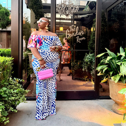 Woman in colorful outfit standing outside a building with 'The Garden Room' sign.
