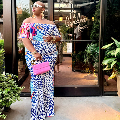 Woman in a colorful dress standing in front of 'The Garden Room' entrance.